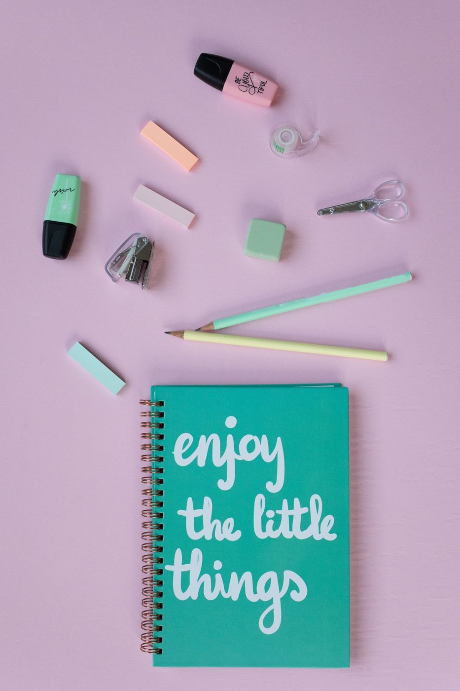 Pastel stationery and a teal notebook on a lilac desk