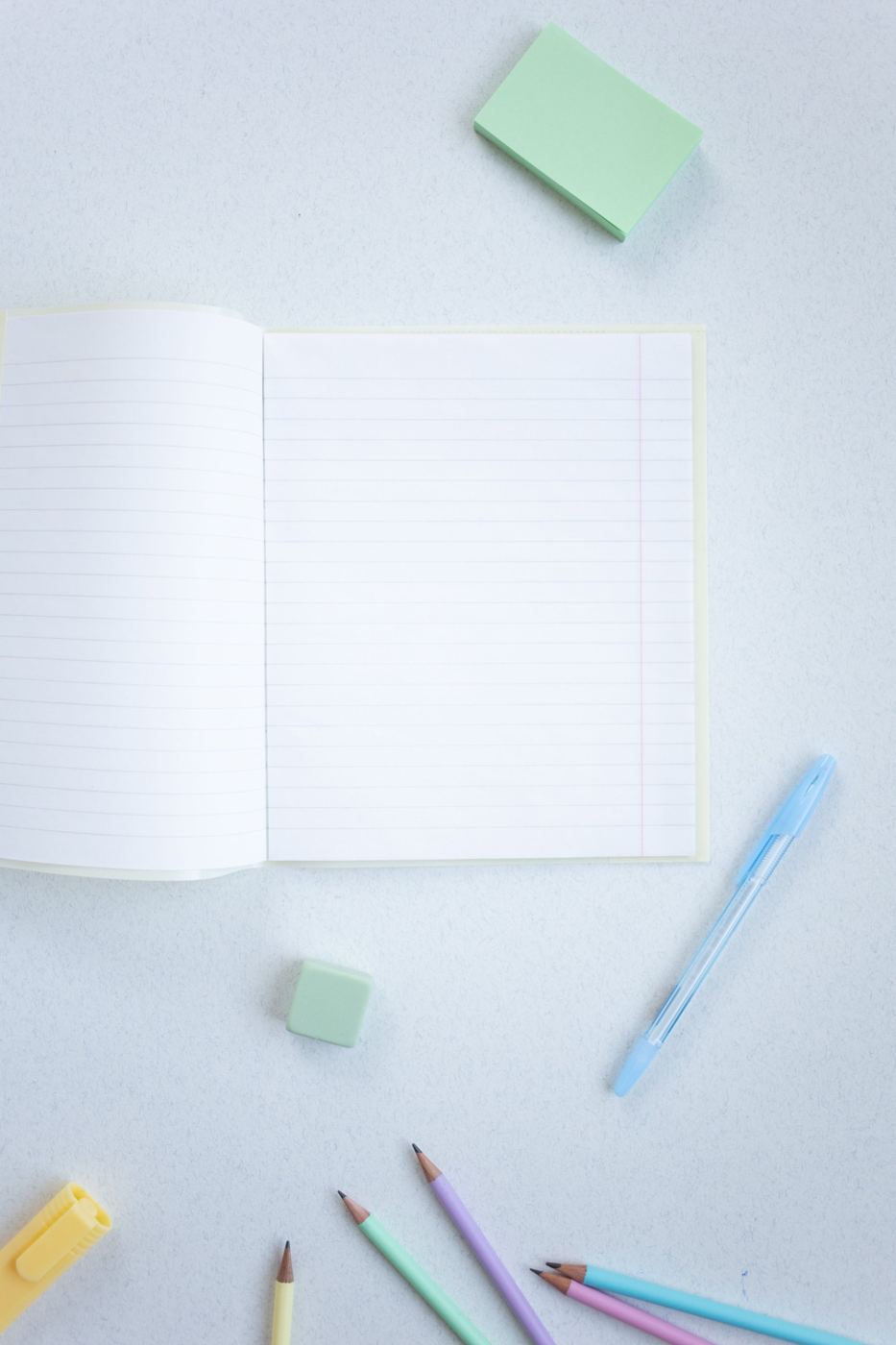 An open lined notebook with pastel pencils and sticky notes