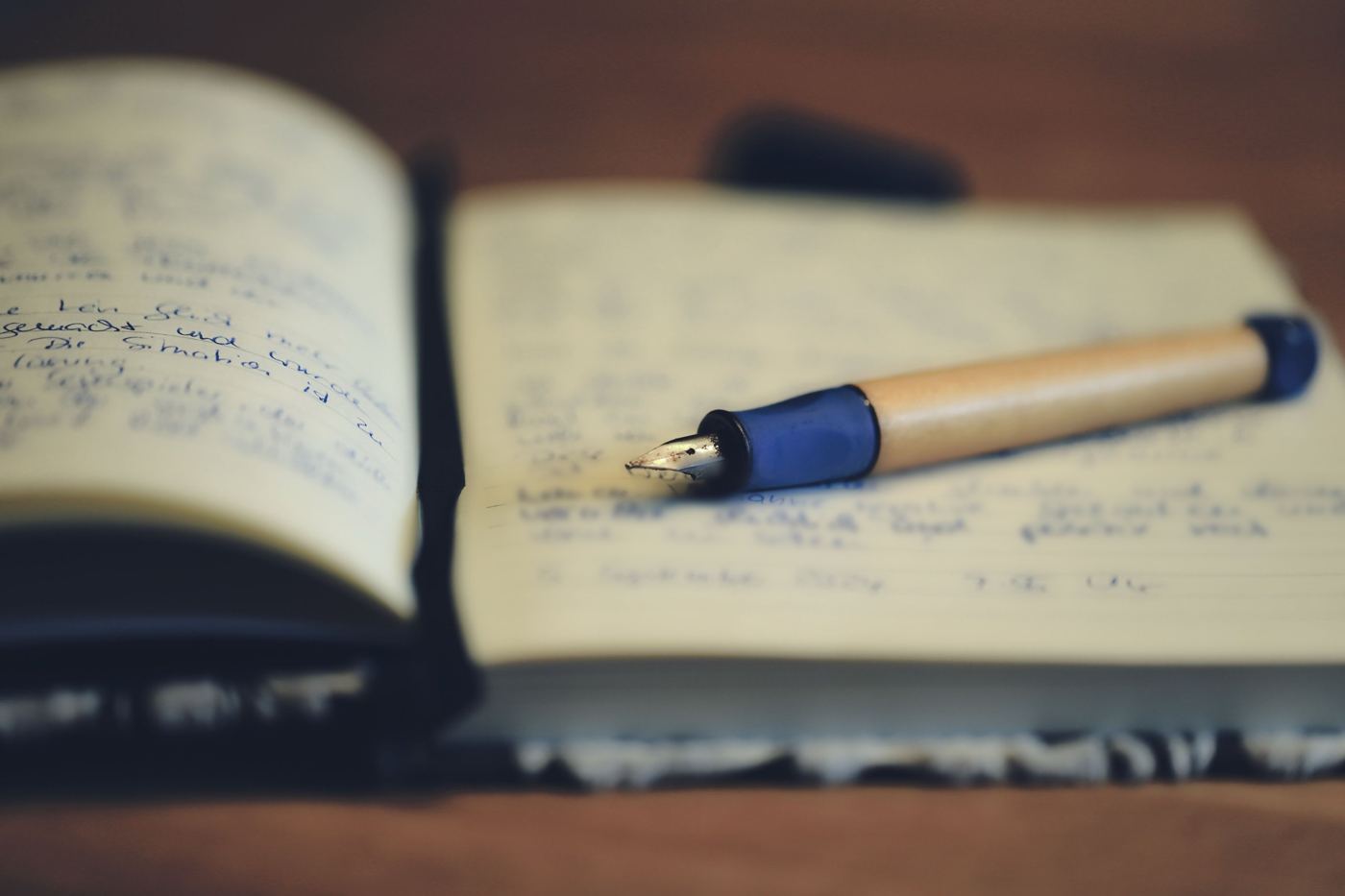 A fountain pen resting on a handwritten notebook